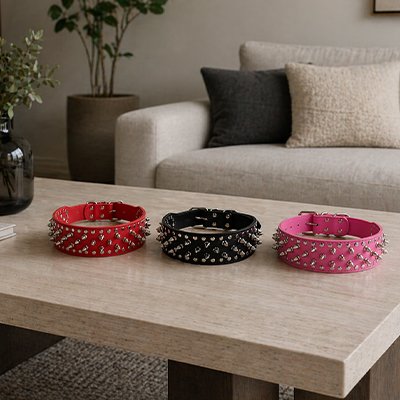 trois colliers chien cloute cuir rouge noir rose sur table